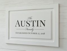 a white frame with the name and date printed on it, hanging on a wall