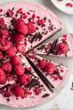 there is a cake with raspberries on it and chocolate shavings around the edges