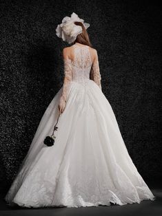 a woman in a white wedding dress standing on a black background with her back to the camera