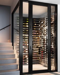 an open wine cellar with stairs leading up to the second floor and glass doors on both sides