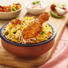 a bowl filled with chicken and rice on top of a wooden table