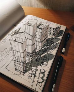 an open notebook with a drawing of buildings on the page and pen next to it