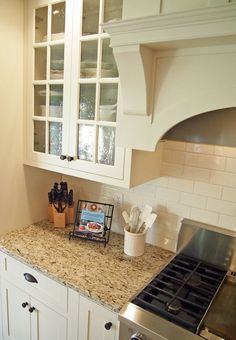 a kitchen with white cabinets and granite counter tops, along with a stove top oven