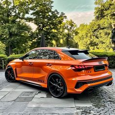 an orange car parked in front of some trees