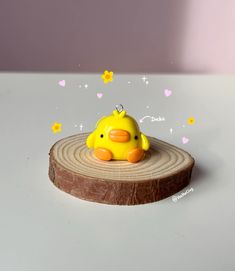 a yellow rubber duck sitting on top of a wooden slice