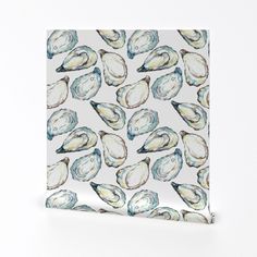 a white and blue tile with seashells printed on the bottom, in front of a white background