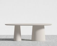 a white table sitting on top of a cement floor next to a gray and white wall