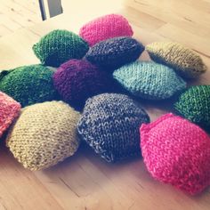 a pile of knitted hats sitting on top of a wooden floor