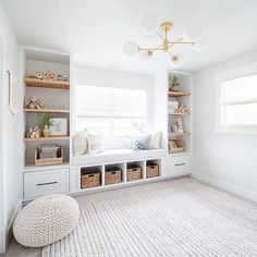 a white room with lots of shelves and baskets on top of the shelf, along with a large rug