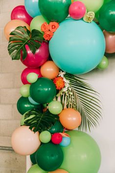 a bunch of balloons that are hanging from a wall