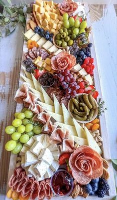 an assortment of cheeses, fruits and meats on a platter