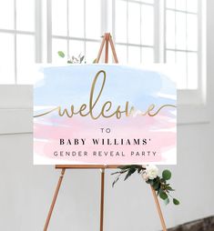 a welcome sign with flowers and greenery sits on an easel