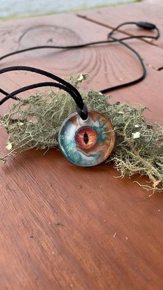 This handcrafted dragon eye necklace is a unique piece that is sure to be a statement pieces. I created this epoxy resin necklace with a glass faux eye that I have encased in eco epoxy resin. The background is swirled copper, hunter green, and white colored epoxy resin. This pendant will make a special gift for him. -Pendant Sizing- 1 inch diameter  -This pendant includes a pull apart clasp corded necklace-  -Necklace can be sized from 16-24 inches- -All necklaces include a small necklace box or Dragon Eye Necklace, Epoxy Resin Necklace, Colored Epoxy Resin, Evil Eye Choker, Corded Necklace, Colored Epoxy, Special Gifts For Him, Necklace Evil Eye, Small Necklace