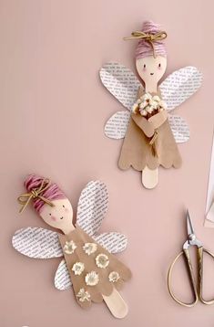 two paper angel cut outs sitting on top of a table next to scissors and other crafting supplies