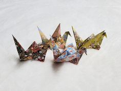 three origami cranes sitting on top of a snow covered ground next to each other