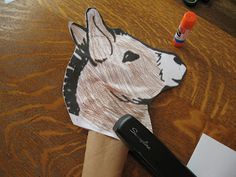 a paper cut out of a dog's head on a table next to an orange marker