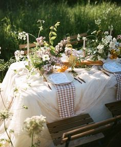 the table is set with flowers and place settings for guests to sit down at it