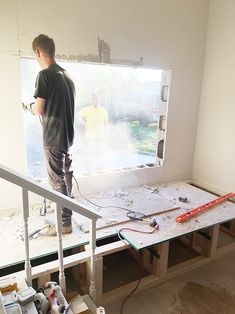 a man standing on top of a hard wood floor in front of a window under construction