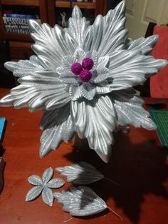 a silver flower with purple center sitting on top of a table next to other decorations