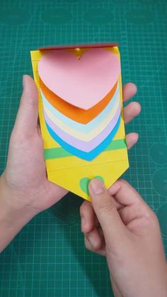 someone is making a heart shaped box out of construction paper