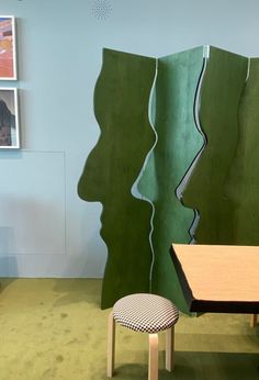 a room with green walls and pictures on the wall, including a table and stool