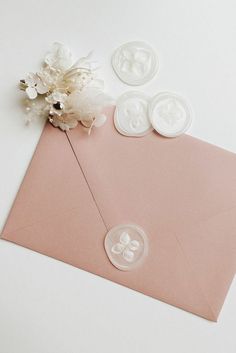 a pink envelope with buttons and flowers on the inside is laying next to some other items