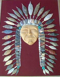 a wooden mask with feathers on it's head is displayed against a red background