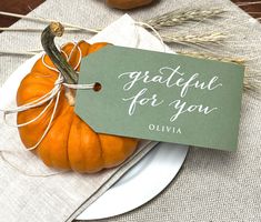 a table setting with pumpkins and place cards