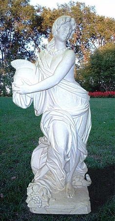 a white statue sitting on top of a lush green field