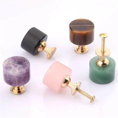 four different colored wooden knobs with gold plated handles and one has a purple stone in the middle