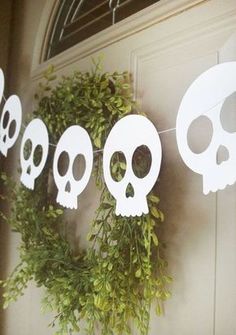 a wreath with paper skulls hanging from it's sides next to a front door