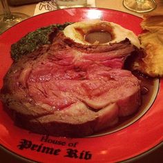 a red plate topped with meat and veggies