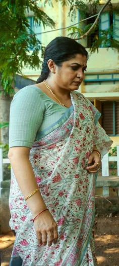 a woman in a sari walking down the street with her hand on her hip