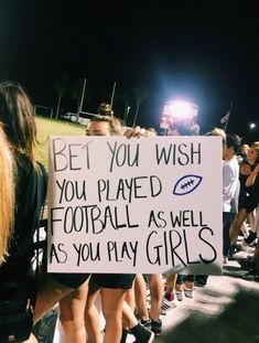 a group of people standing around each other holding a sign that says be you wish you played football as well as you play girls