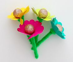 three paper flowers with glittered centers on them sitting next to each other in front of a white background