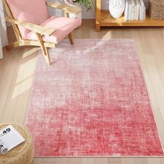 a living room with a pink chair and rug on the hardwood floor, in front of a white wall