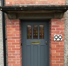 the front door to a brick building with a number sign on it