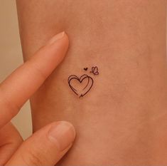 a small heart tattoo on the side of a woman's left arm and wrist