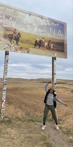 a woman standing under a sign in the middle of nowhere