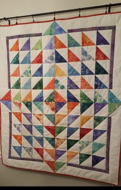 a multicolored quilt hanging on a wall