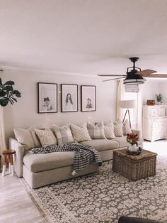 a living room filled with furniture and pictures on the wall next to a rug in front of a window