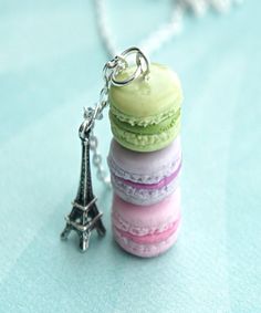 a stack of macaroons sitting next to the eiffel tower on a chain