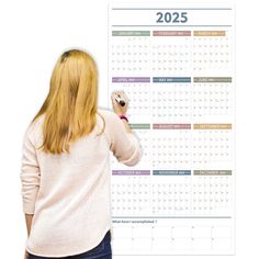 a woman writing on a wall calendar