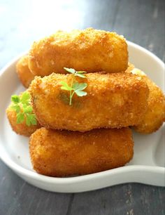 fried potato croquettes with ham and cheese on a white plate, topped with parsley