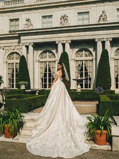 a woman standing in front of a building wearing a wedding dress