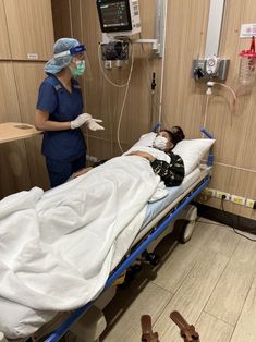 a woman laying in a hospital bed next to a nurse