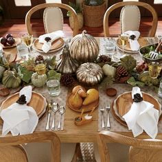 the table is set for thanksgiving dinner with silverware and pumpkins, pine cones, acorns, and other autumn decorations