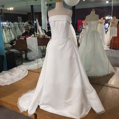 wedding gowns are displayed in a store window with mannequins behind them