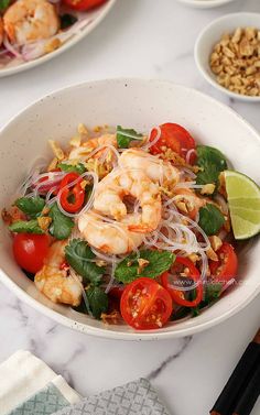 a white bowl filled with shrimp and veggies on top of a marble counter