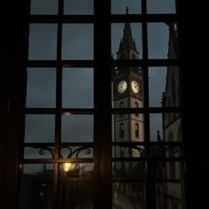 a clock tower seen through a window at night